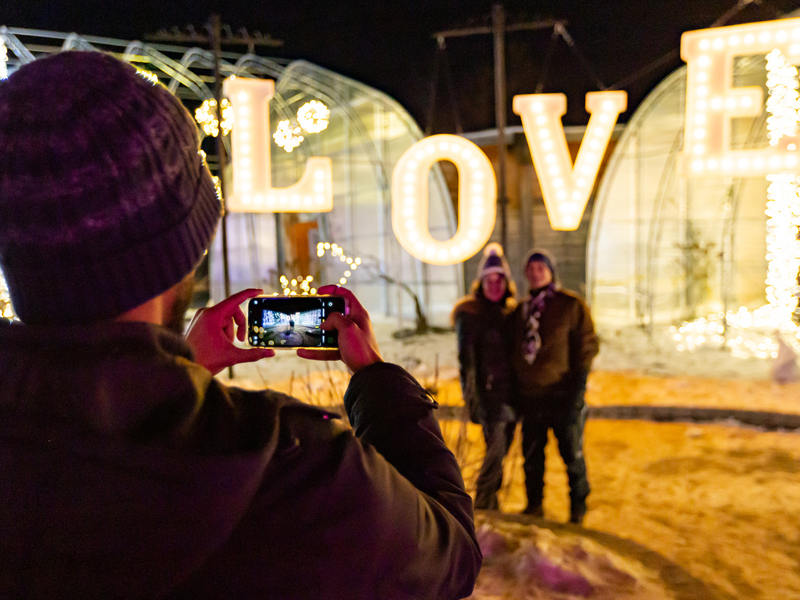 couple has their photo taken in front of a large lit up LOVE sign